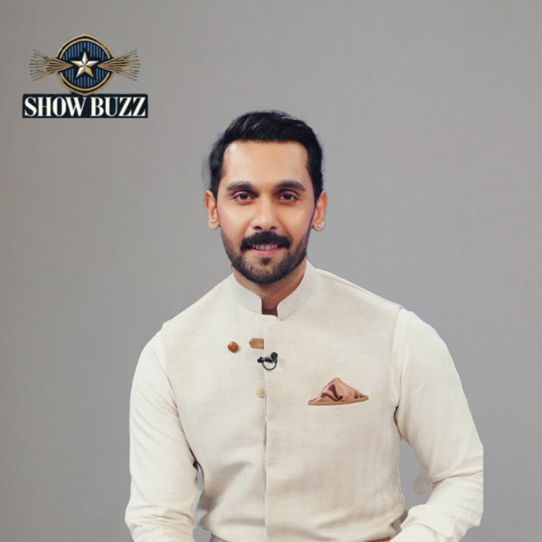 Man in a stylish beige traditional jacket with a brown pocket square, smiling under the ShowBuzz logo